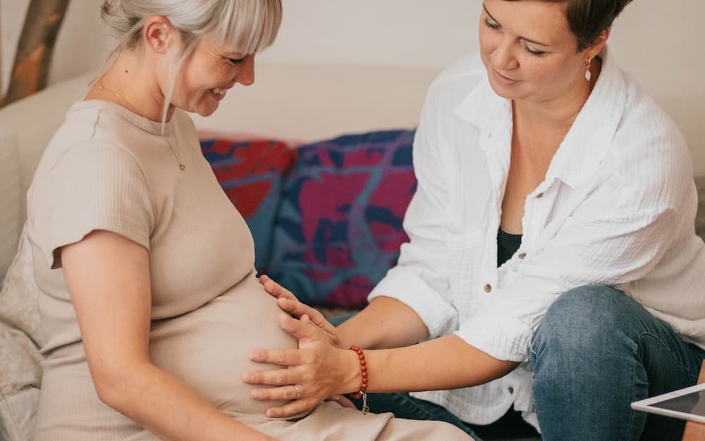 nahaufnahme von steffi mit händen auf dem babybauch einer kundin